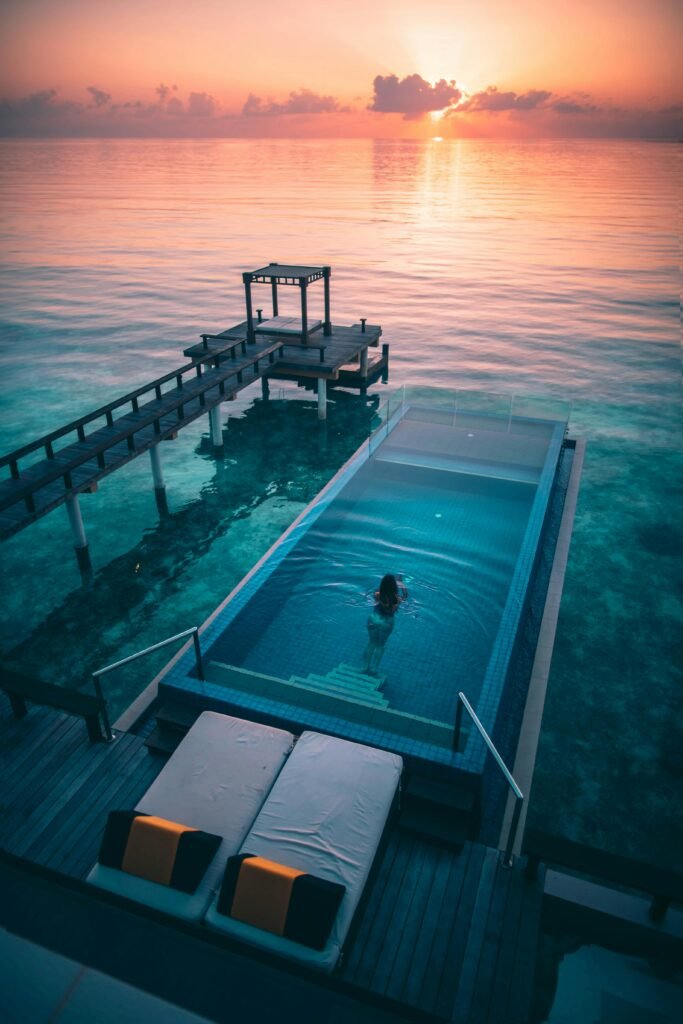 Experience ultimate relaxation at a luxury Maldives resort with an infinity pool overlooking the ocean at sunset.