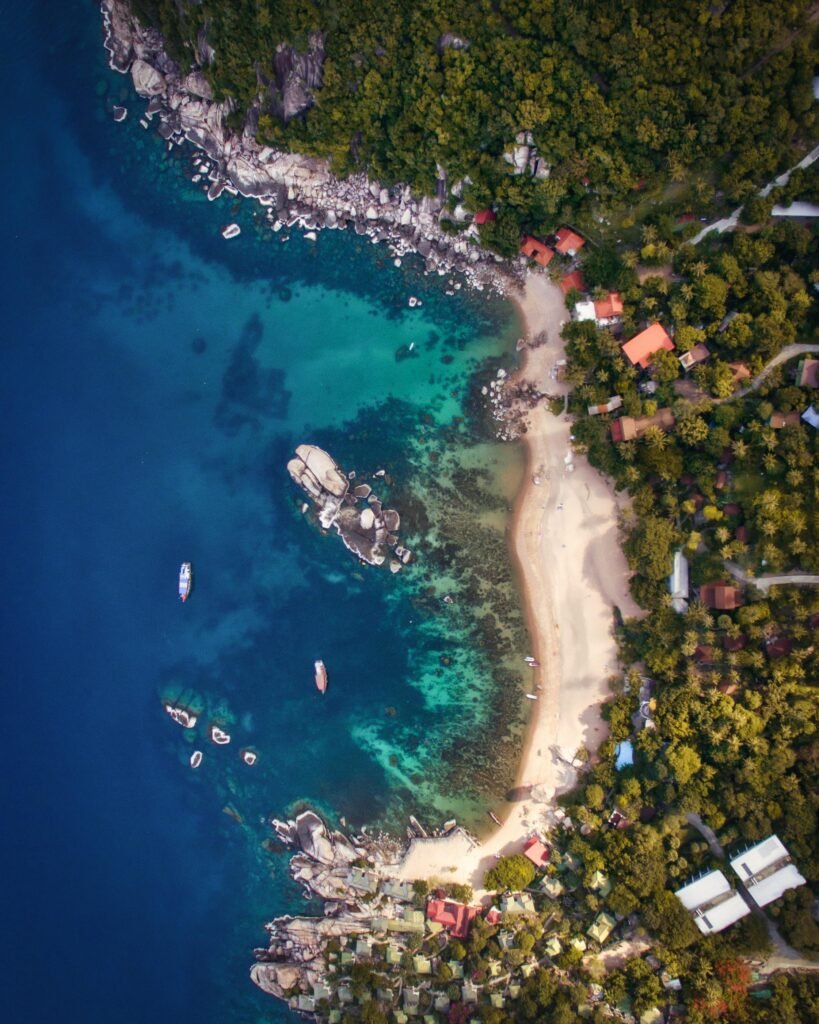 Stunning aerial shot of a secluded beach on Ko Tao island, Thailand, with clear blue waters and lush greenery.