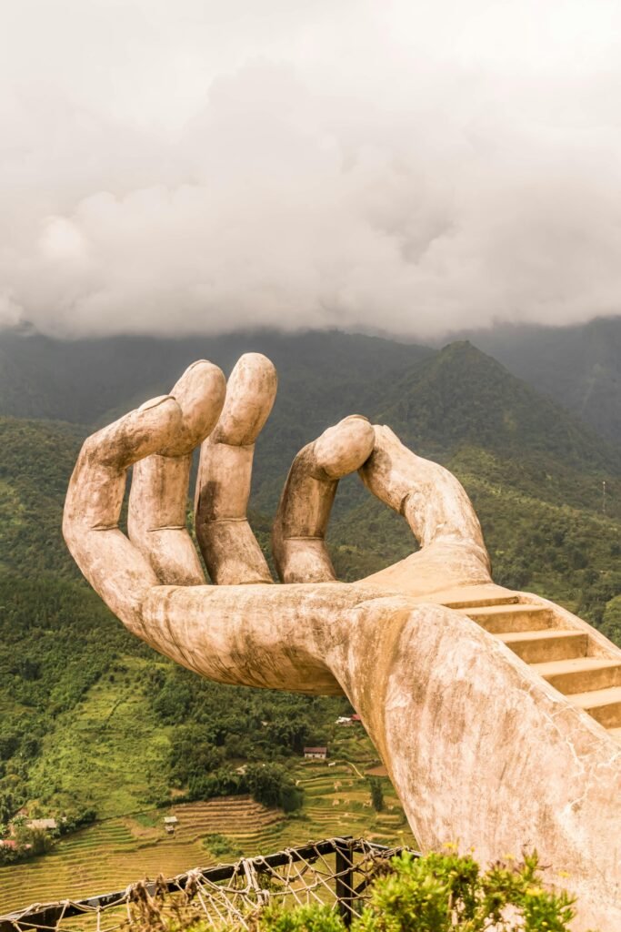 Stunning stone hand sculpture in Vietnam's lush landscape, offering scenic views over the hills.