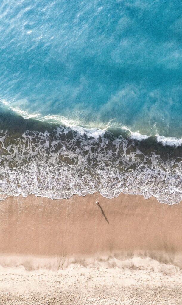 Vibrant aerial capture of Arugam Bay's sandy shore and turquoise waves.